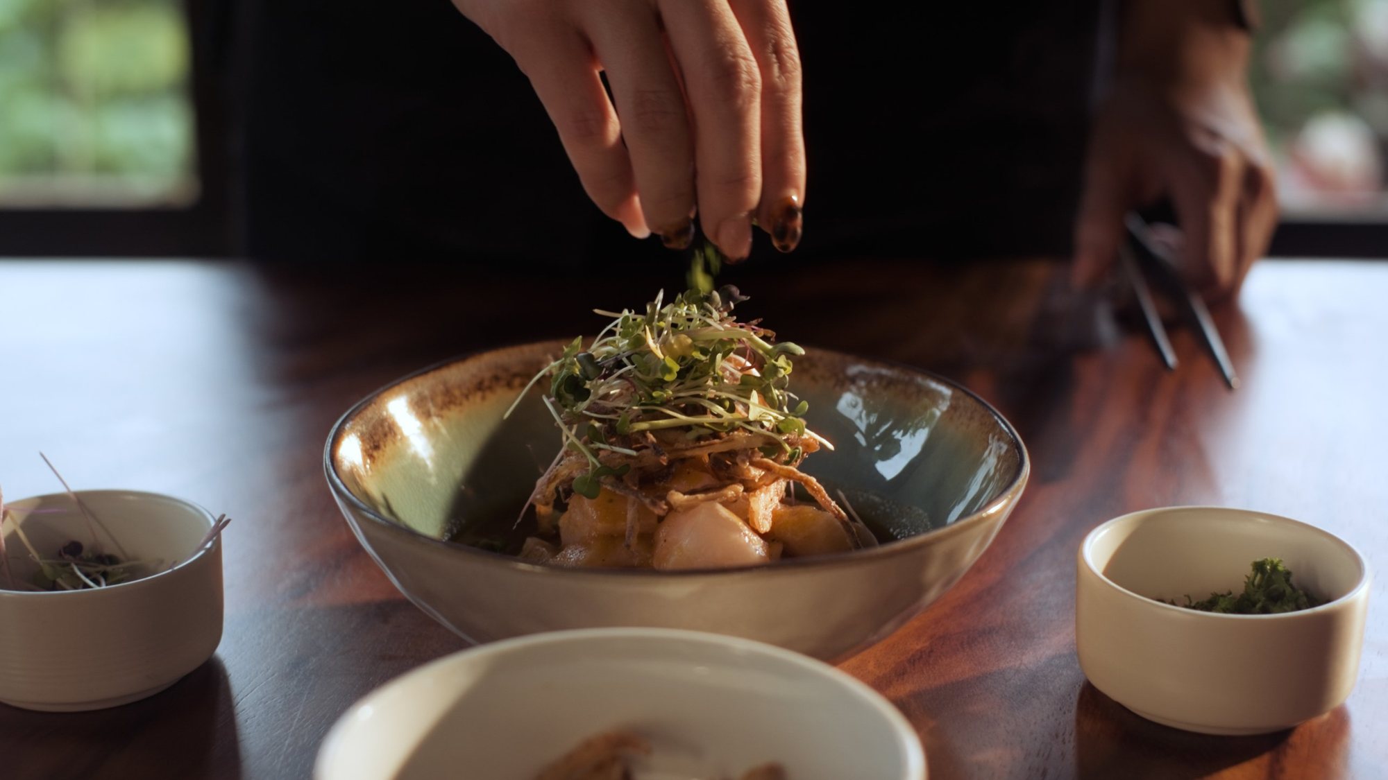 Chef finishing a ceviche with fresh microgreens at El Sendero
