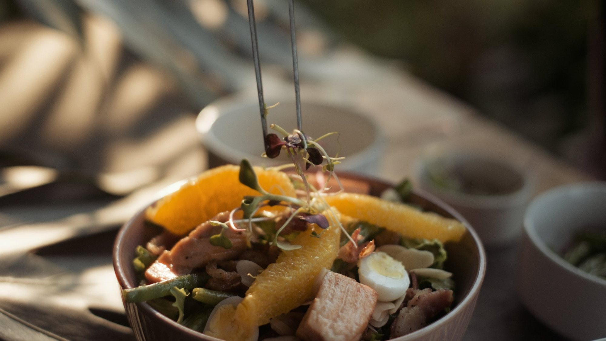 Salmon salad with orange, quail egg and almonds, finished with microgreens